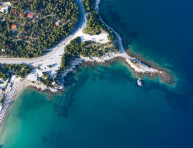 Aerial view from flying drone of a small peninsula with calm turquoise sea water.